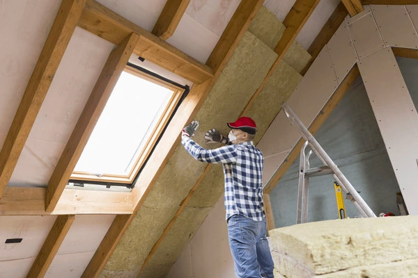 Artisan couvreur réalisant le soufflage d'un isolant thermique dans les combles perdus d'une maison à Lacanau